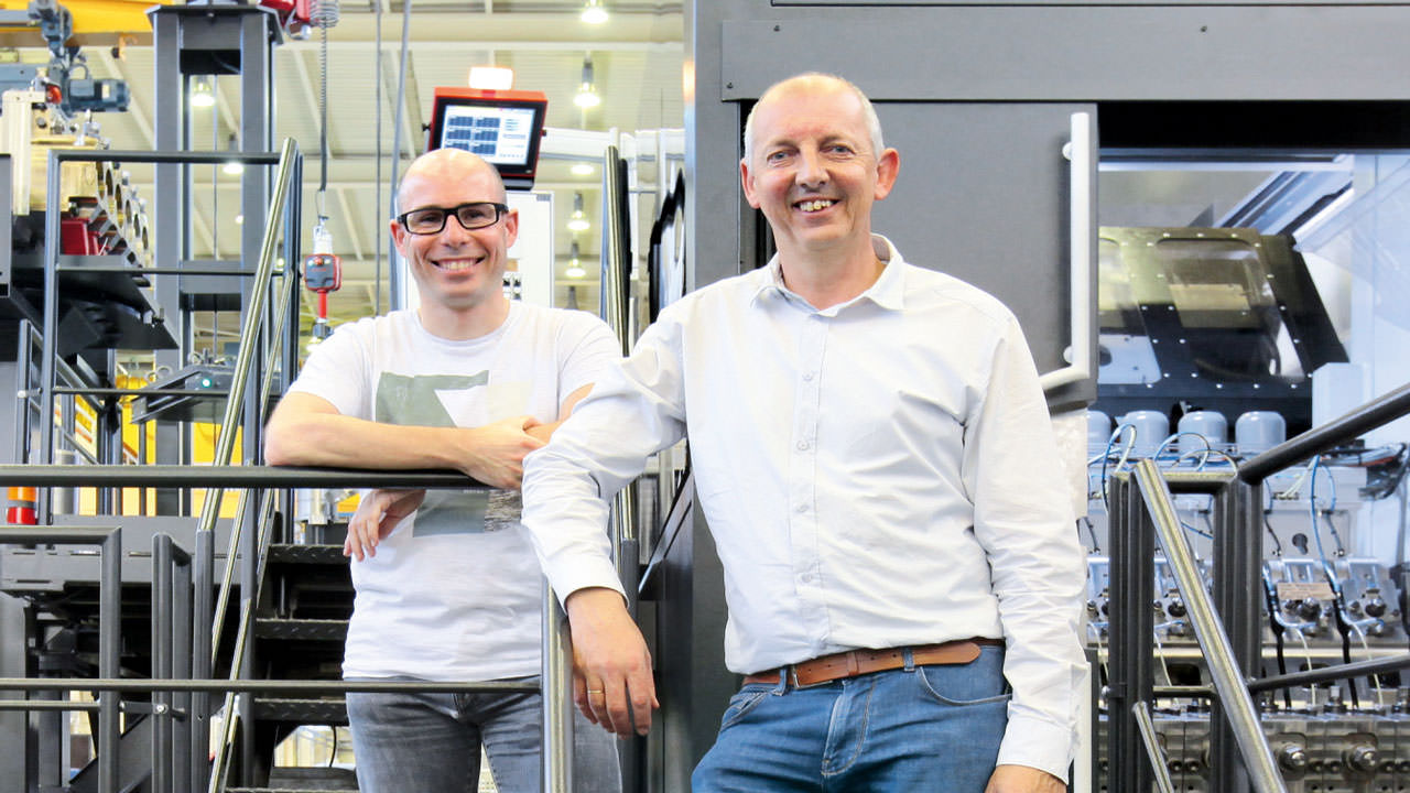 Tom van Weert, Programmer, and Ivo Van Gorp, Coordinator/Developer Automation at Nedschroef, in front of the forming machine (from left to right). 